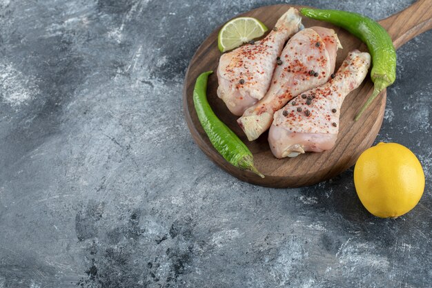 raw spicy chicken drumsticks with green pepper and lemon.