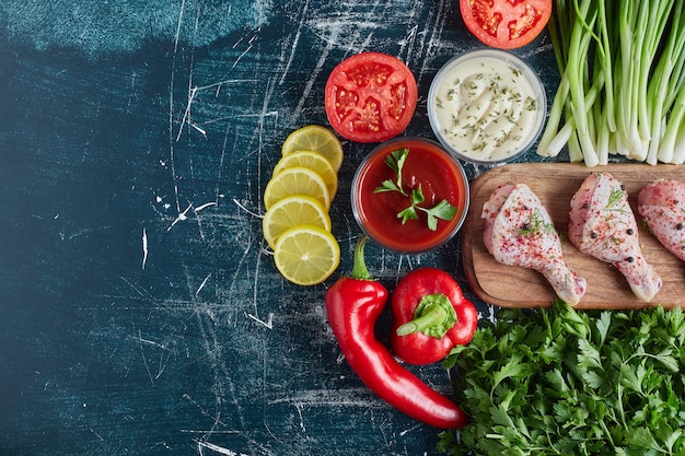 Raw spicy chicken legs on a wooden board.