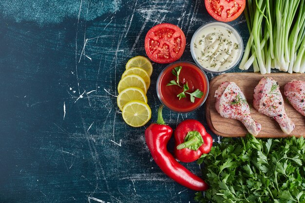 Raw spicy chicken legs on a wooden board.