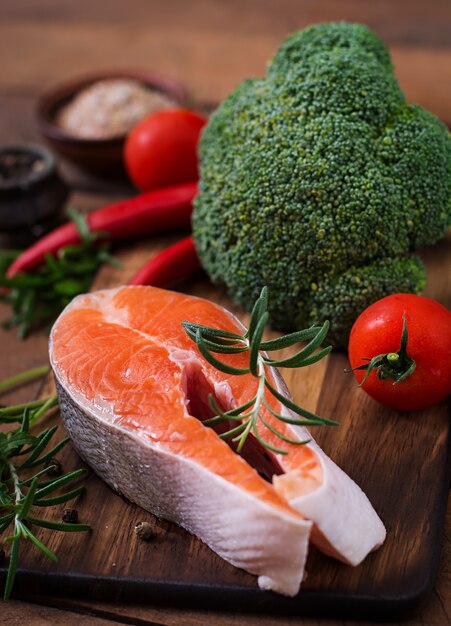 Raw steak salmon and vegetables for cooking on wooden table in a rustic style. 