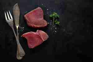 Free photo raw tuna slices with salt on dark background.