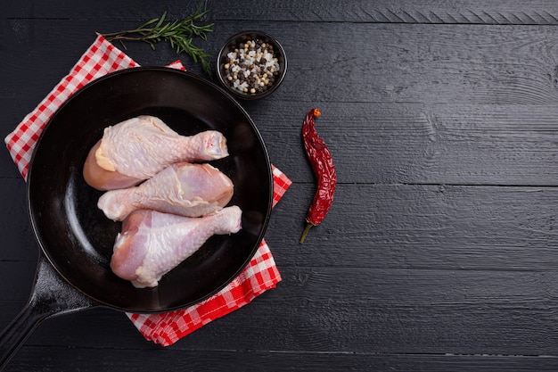 Raw uncooked chicken legs on the dark wooden surface.