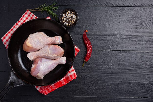 Raw uncooked chicken legs on the dark wooden surface.