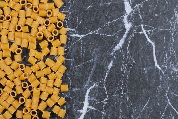 Free photo raw uncooked pasta penne on stone black.