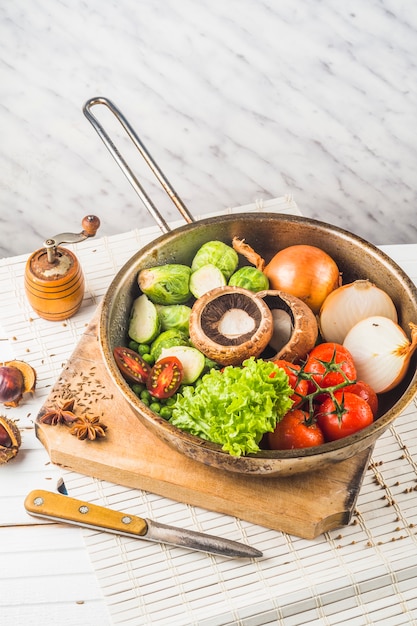 Raw vegetables in old vintage pan over the chopping board