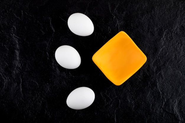 Free photo raw white eggs and small bowl on black surface.