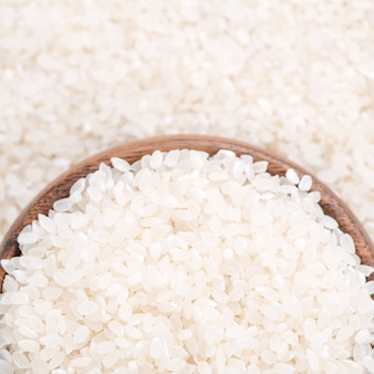 茶色のボウル、有機農業のデザインコンセプトの白い背景に生の白い磨かれた製粉食用米作物。アジアの主食、クローズアップ。