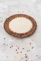 Free photo raw white rice in wooden circular plat over concrete surface