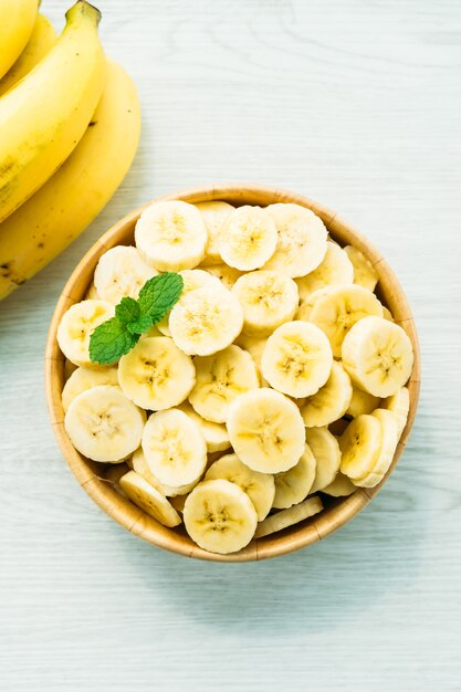 Raw yellow banana slices in wooden bowl