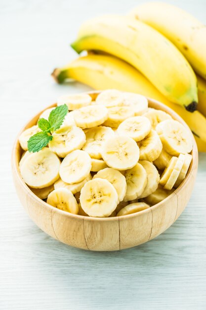 Raw yellow banana slices in wooden bowl