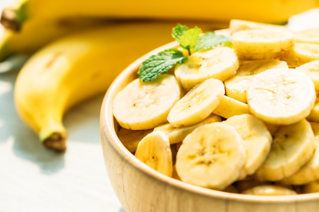 Raw yellow banana slices in wooden bowl