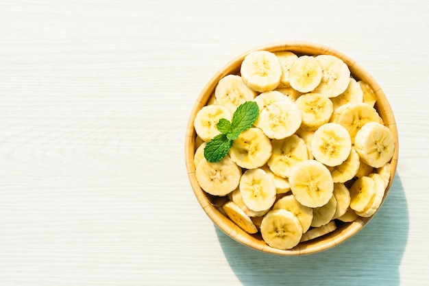 Raw yellow banana slices in wooden bowl