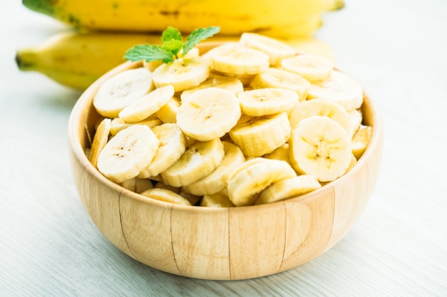 Raw yellow banana slices in wooden bowl