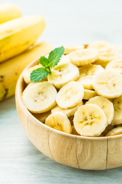 Raw yellow banana slices in wooden bowl