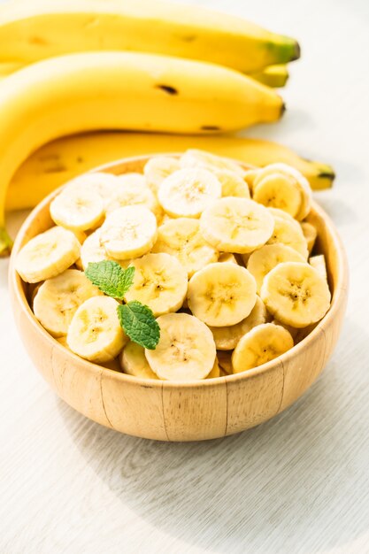 Raw yellow banana slices in wooden bowl