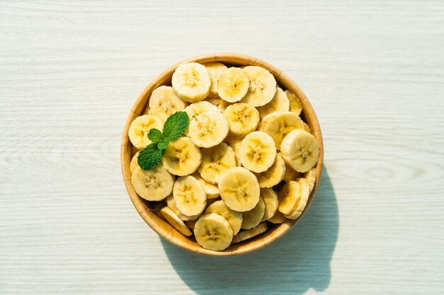 Raw yellow banana slices in wooden bowl