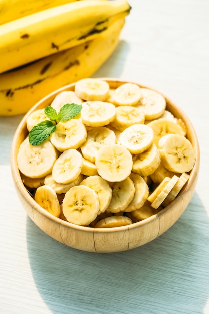 Raw yellow banana slices in wooden bowl