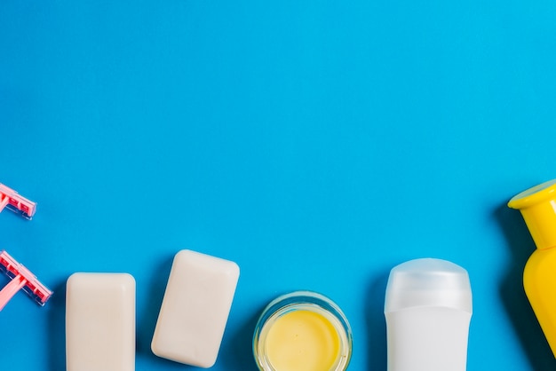 Razor; soap; moisturizer and shampoo bottles on blue background