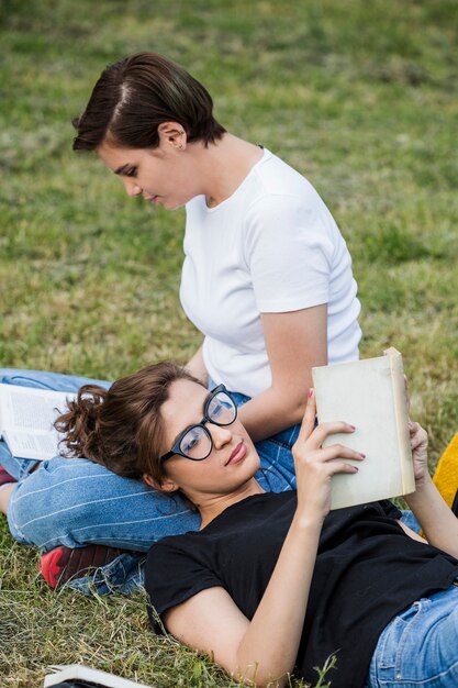 Free photo reading books in park relaxed female friends