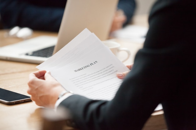 Reading marketing plan concept, businesswoman holding document, close up view