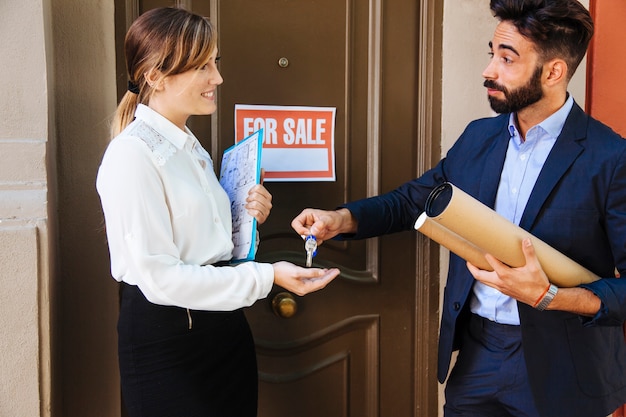 Real estate agent giving key to business woman