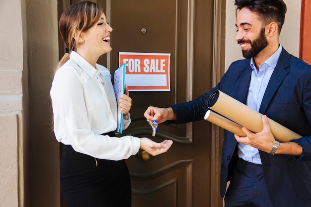 Real estate agent giving key to woman