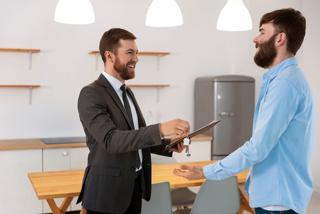 Real estate agent giving keys to new house to male buyer