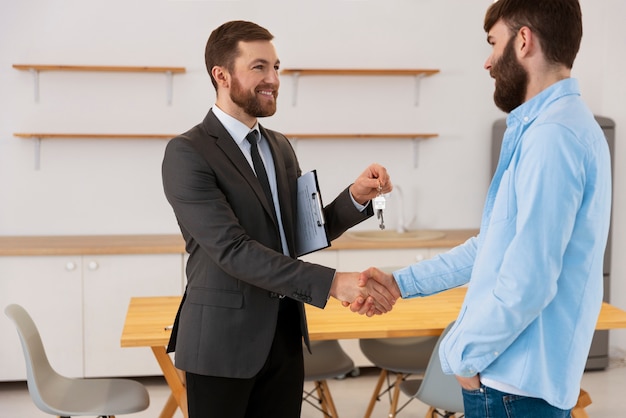 Free photo real estate agent giving keys to new house to male buyer