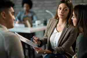 Free photo real estate agent showing the terms of a contract to young couple while analyzing paperwork on a meeting