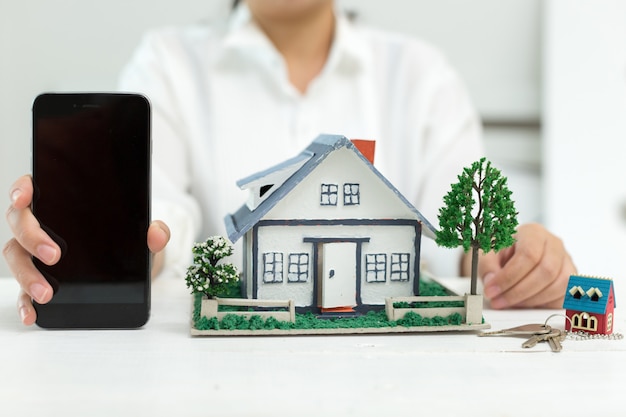 Real estate agent with house model and phone