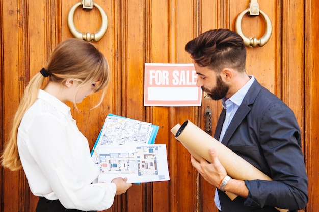 Free photo real estate agents waiting with plans in front of door