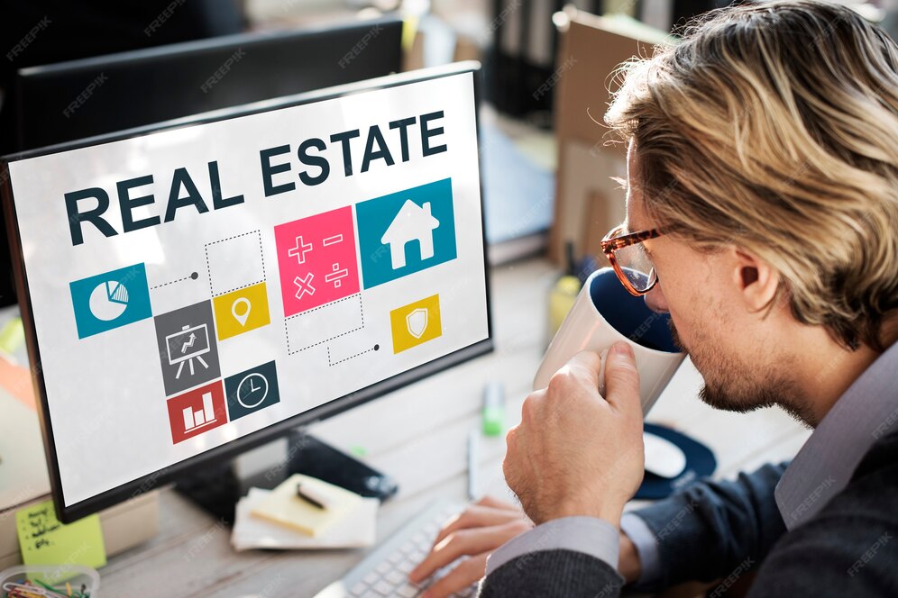 A person holding a cup while working on a computer with real estate written on its screen