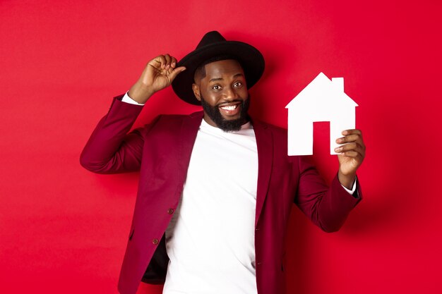 Real estate. Cheerful Black man showing paper house and smiling