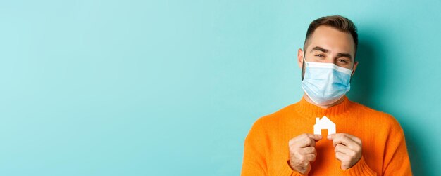 Foto gratuita immobiliare e concetto di pandemia di coronavirus primo piano di un uomo adulto in maschera medica che tiene un piccolo pape