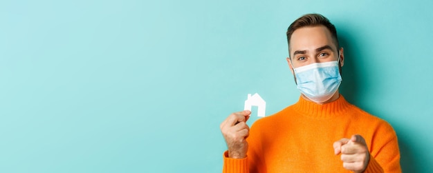 Free photo real estate and coronavirus pandemic concept closeup of adult man in medical mask pointing at you an