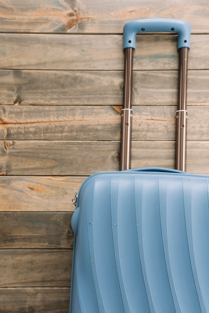 Реалистичный пластиковый чемодан из поликарбоната с ручкой на деревянном фоне