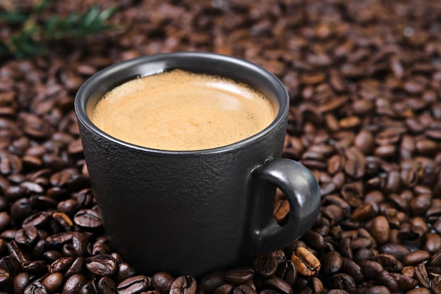 볶은 커피 콩에 있는 어두운 컵에 있는 블랙 에스프레소 커피의 현실적인 전망. 커피 크레마와 커피 콩을 넣은 컵. 컵을 닫고 선택적으로 집중