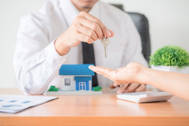 Агент по продаже недвижимости передает ключ от квартиры новому владельцу