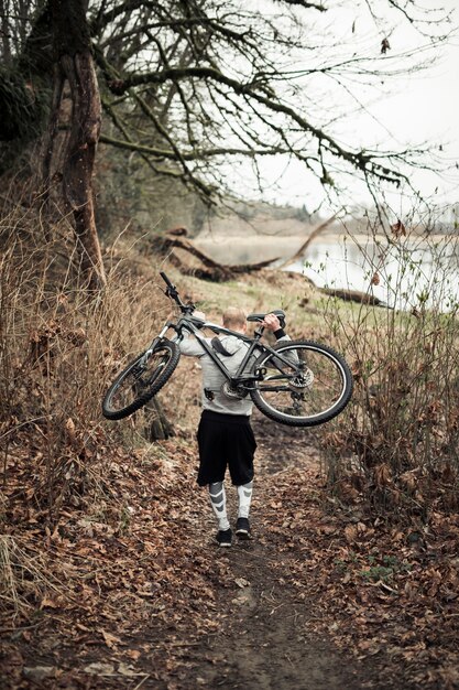 湖の近くを歩いている彼の後ろに自転車を運んでいる男の後ろ