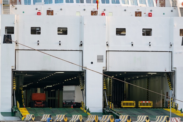 The rear opened doors of a shipping ferry to let the cars get inside the ferry