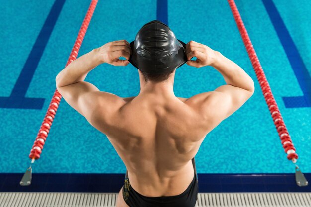 Rear top view of a man putting a cap on