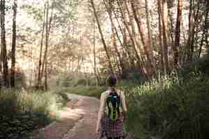 Foto gratuita le vie posteriori della donna che camminano sulla strada non asfaltata nella foresta