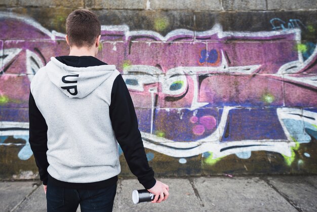 Rear view of a artist standing in front of graffiti wall