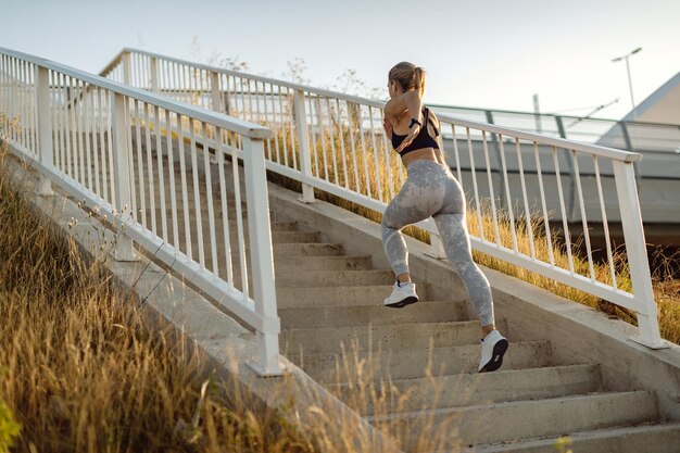 Rear view of athletic woman running up the stairs outdoors