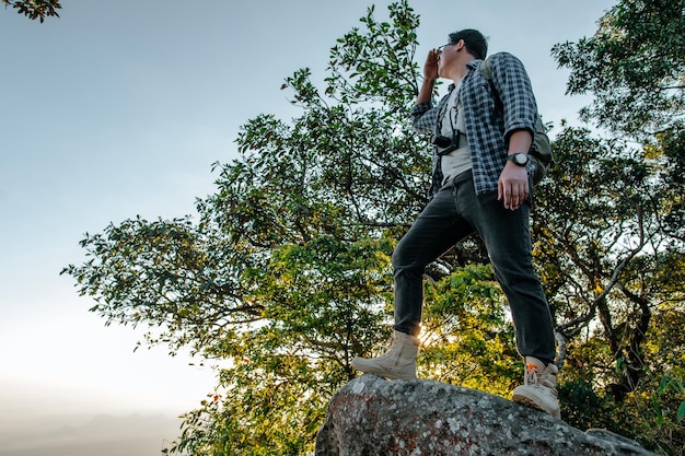 Rear view back of Young asian hiking man standing at view point and looking beautiful view with happy on peak mountain and sunray  copy space