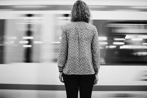 Вид сзади белокурая женщина, ожидающая на платформе поезда