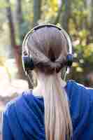 Free photo rear view of blonde woman listening to music in the forest