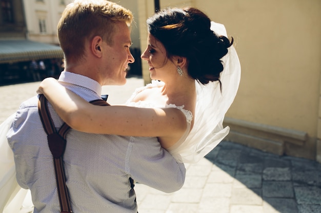 Foto gratuita vista posteriore della sposa tra le braccia dello sposo