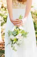 Foto gratuita retrovisione di una sposa con la mano dietro lei indietro che tiene il mazzo del fiore