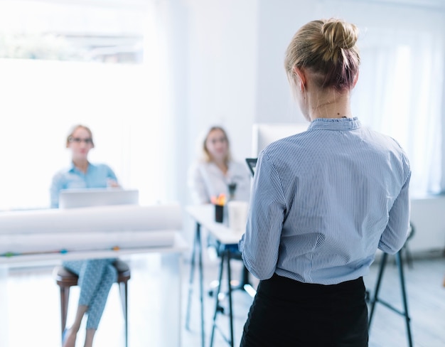 Retrovisione di una donna di affari che dà presentazione nella riunione